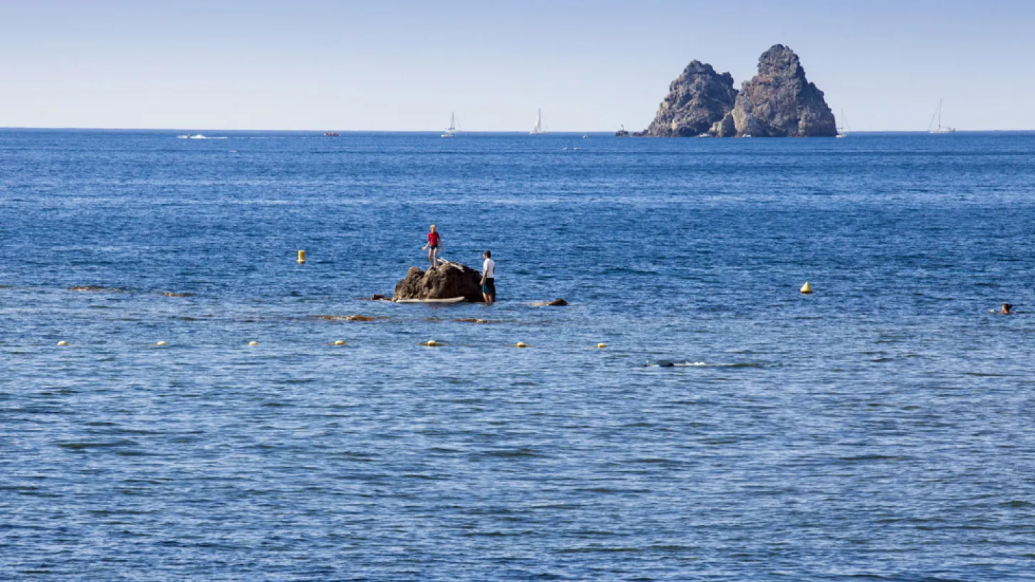 Les deux frères à La Seyne-sur-Mer : vue sur la mer bleu avec en premier plan 2 enfant qui se trouvent sur un gros rocher au milieu de l'eau avec les 2 Frères en fond.