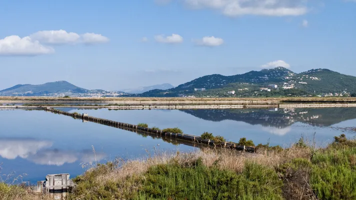 Marais salants des Salins d'Hyères reflétant des collines parsemées d'habitations.